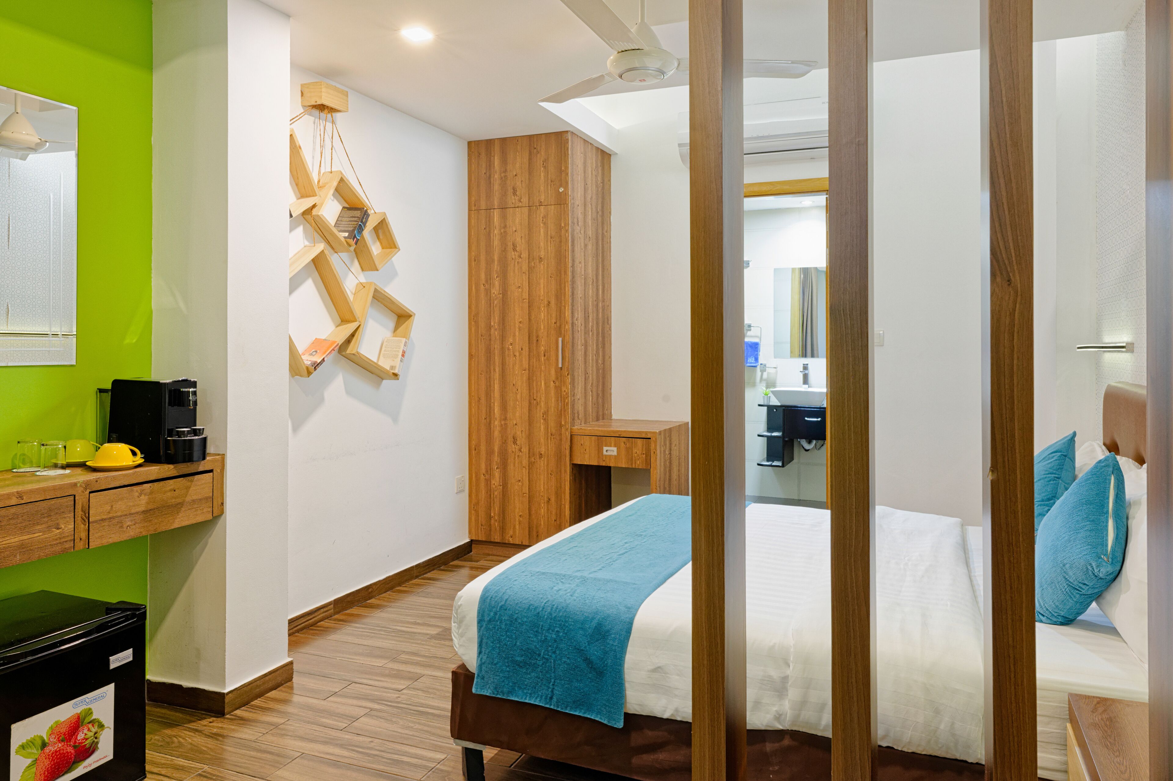 Habitación de hotel con cama, armario de madera, escritorio y pared verde.