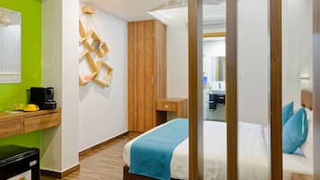 Habitación de hotel con cama, armario de madera, escritorio y pared verde.