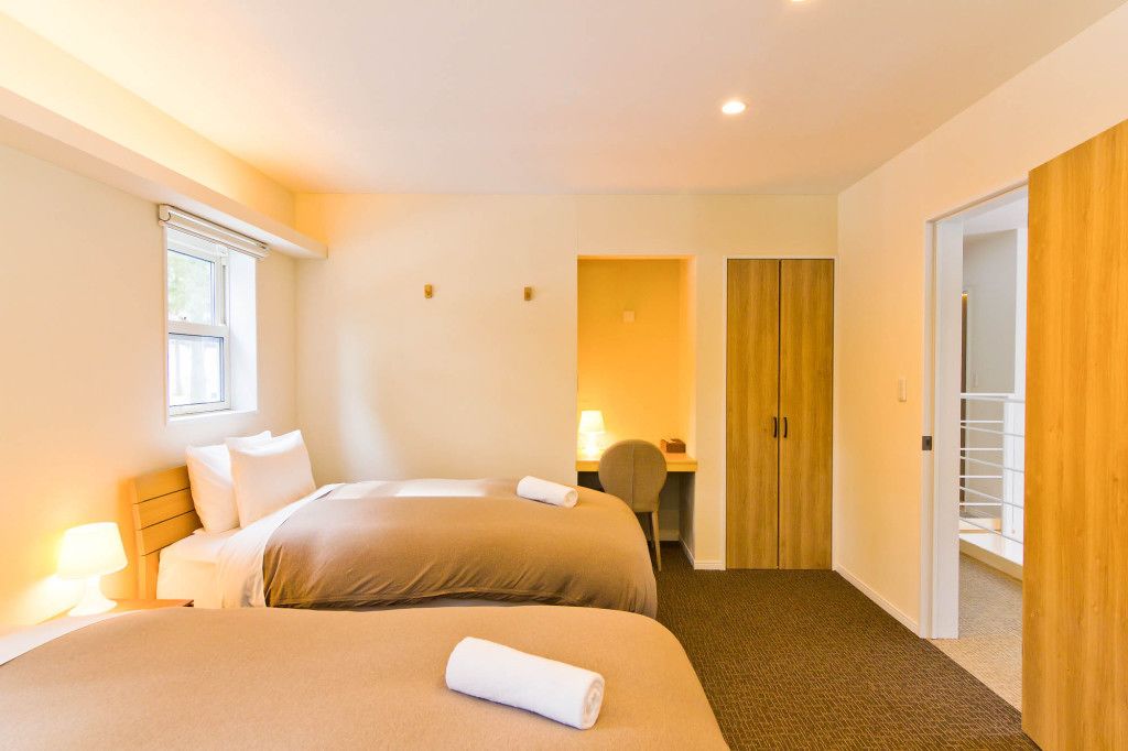 A hotel room with two beds, a desk, and a wardrobe.