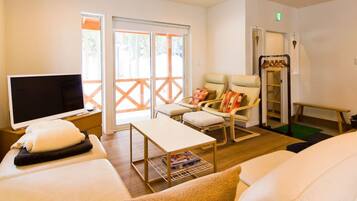 A room with a bed, a TV, a chair, a table, and a window.