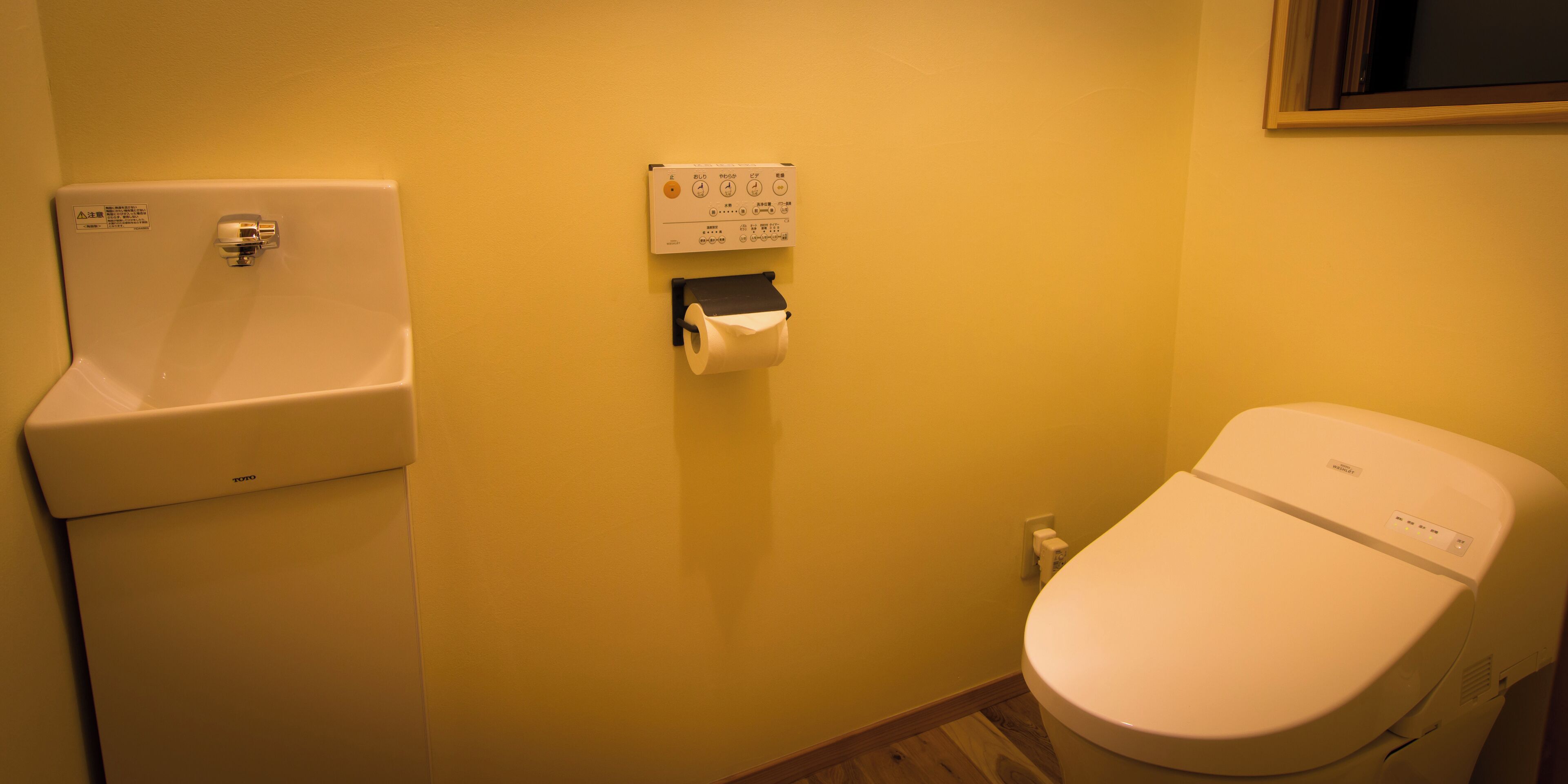 Un baño con inodoro, lavamanos y dispensador de toallas de papel.