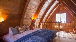 A wooden cabin bedroom with a bed, pillows, and a window. - Morino Lodge Chalets (Hakuba)