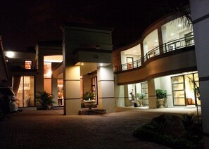 Un hôtel à plusieurs étages doté d’une cour intérieure, de grandes fenêtres et d’une entrée bien éclairée.