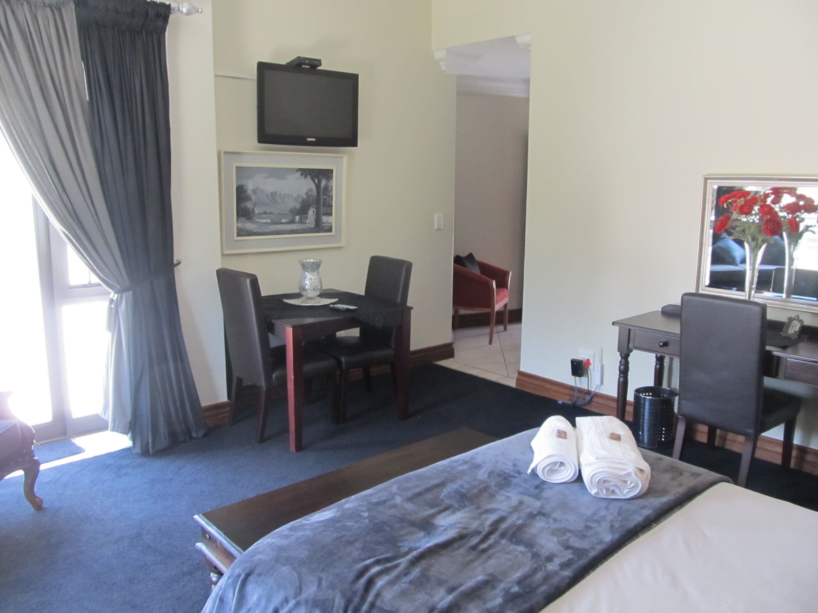 Una habitación de hotel con cama, escritorio, silla, televisión y mesa de comedor.
