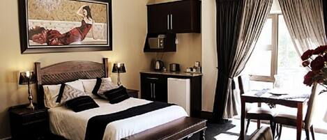 A hotel room with a large bed, bedside tables, a desk, and a chair.