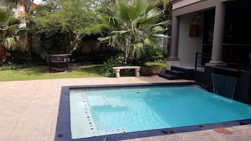 Una piscina al aire libre, sombrillas, tumbonas