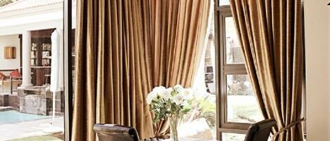 Una habitación con una mesa de comedor, dos sillas y una ventana con cortinas.