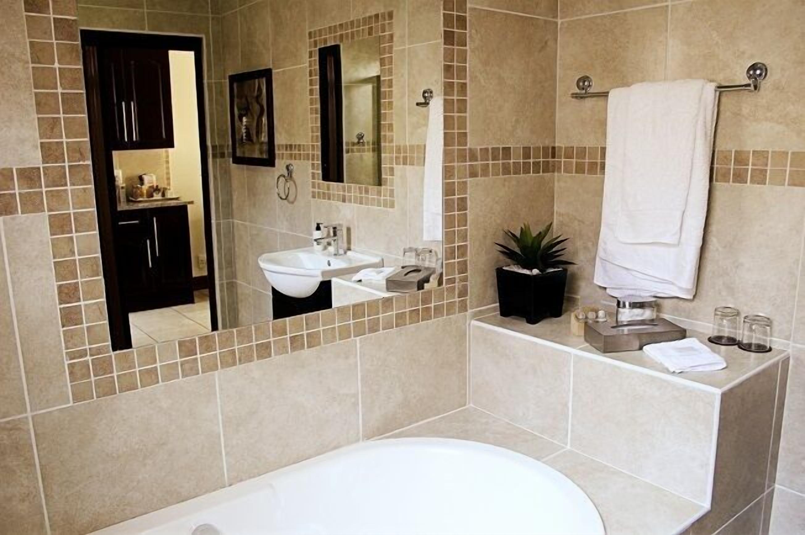 Un baño moderno con bañera, lavamanos y espejo.