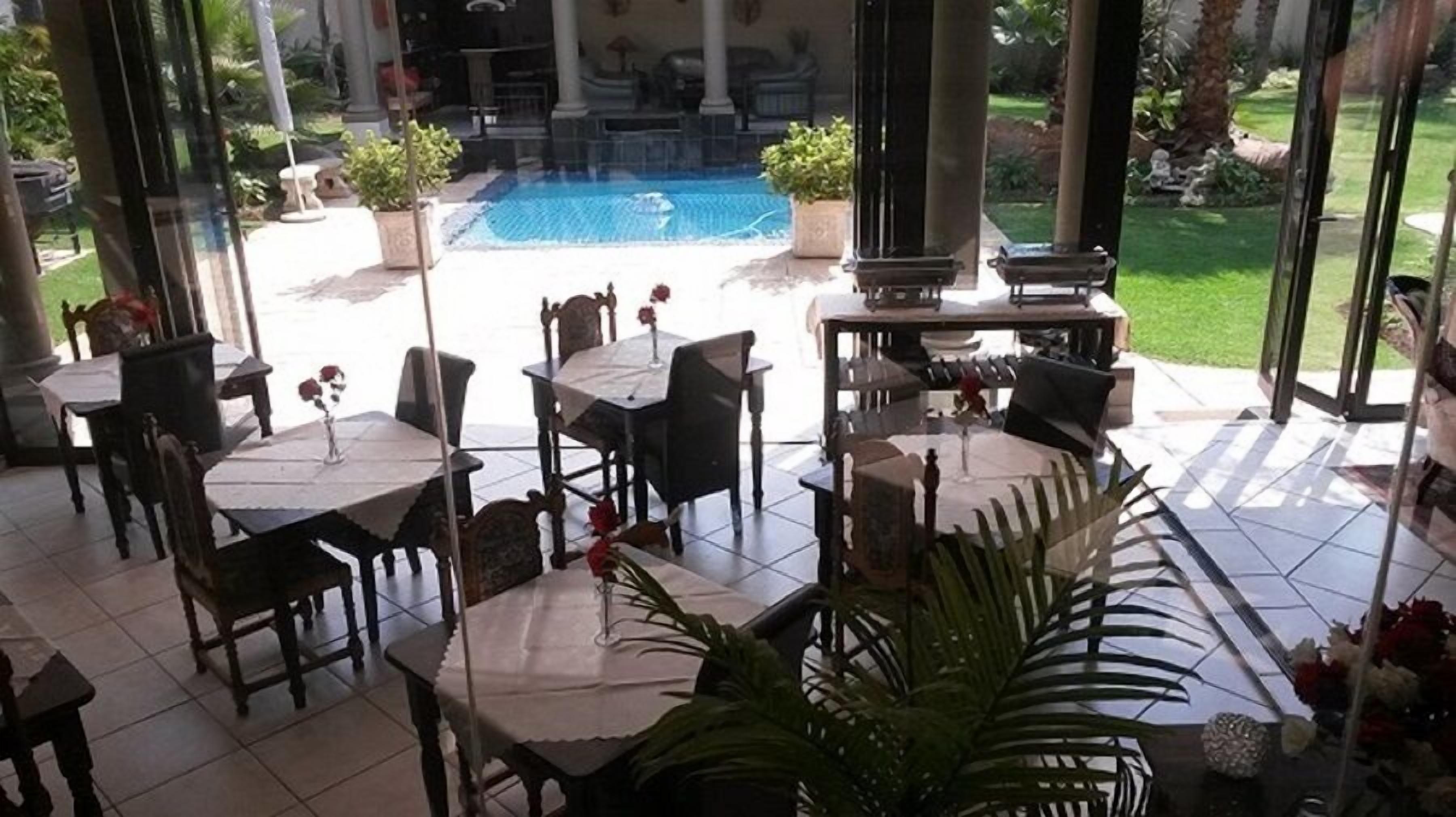 An outdoor patio with tables and chairs, a pool, and a view of the pool area.