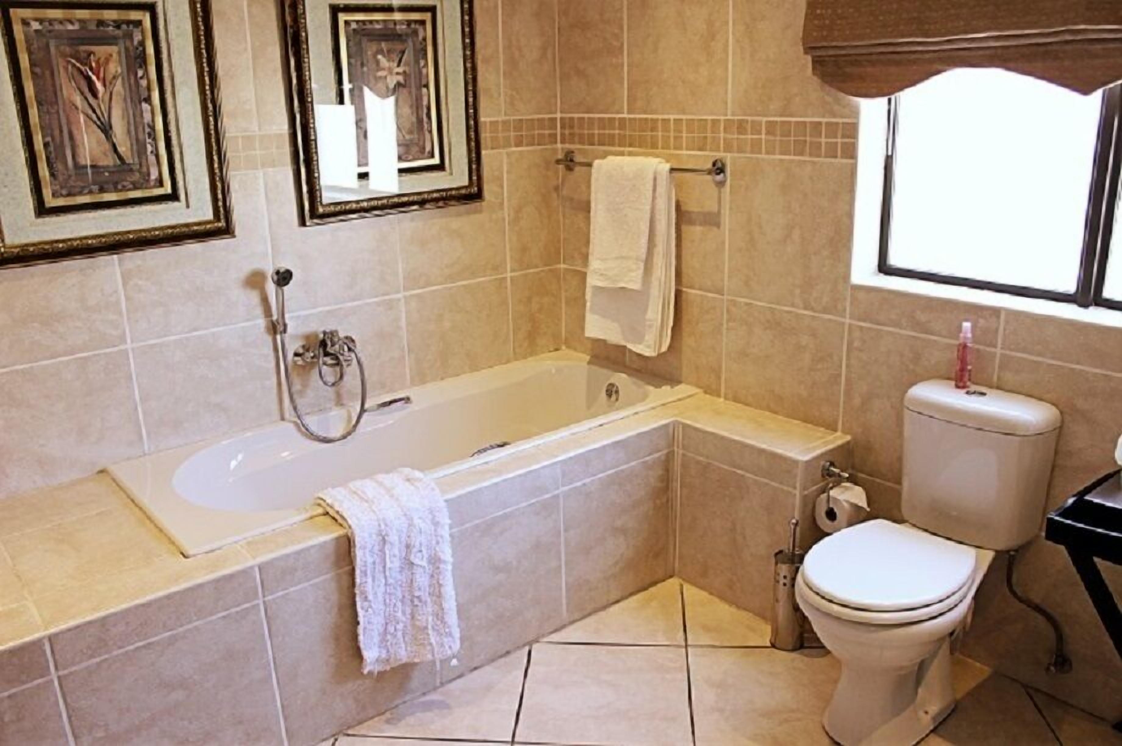 A bathroom with a bathtub, toilet, and a window.
