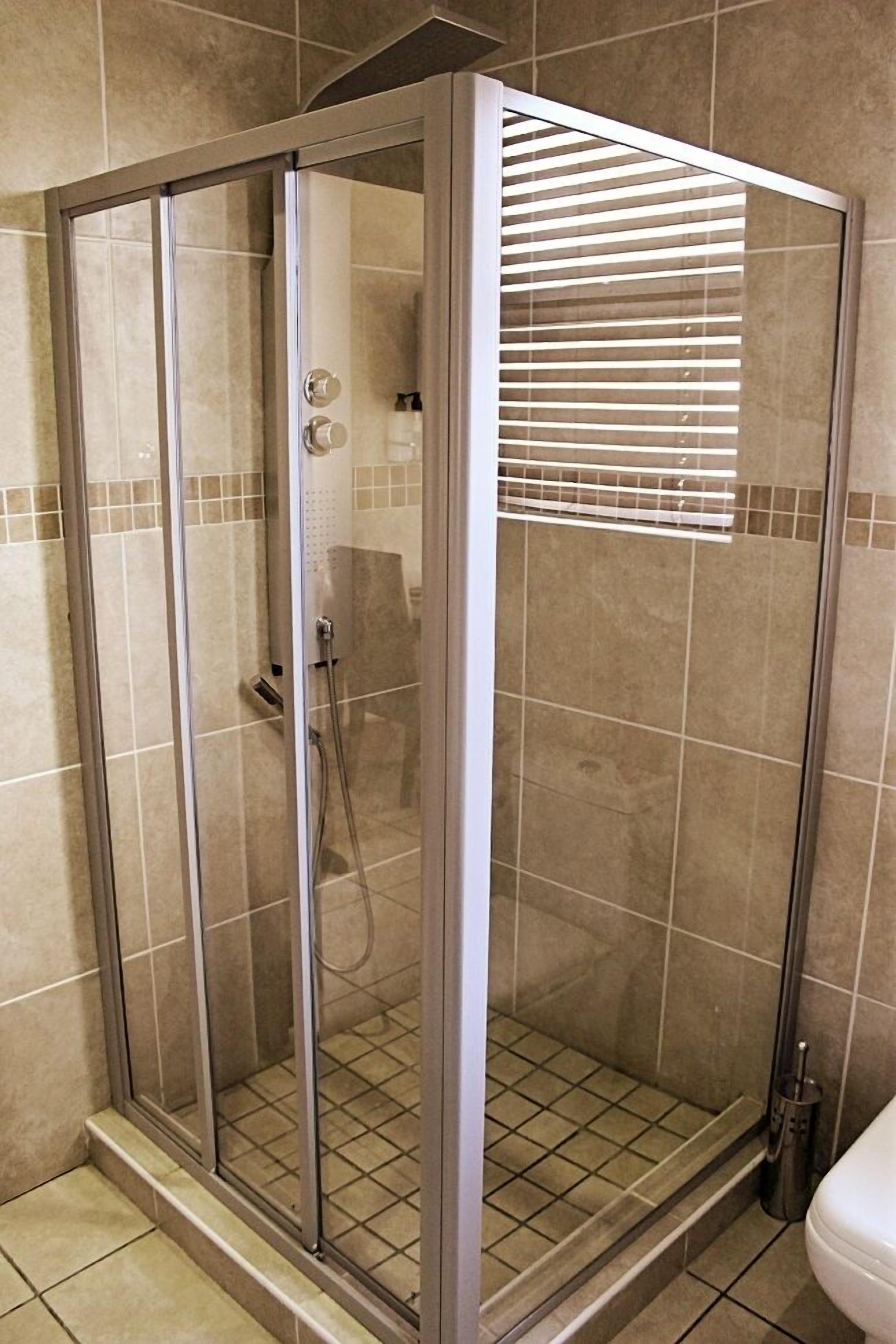 A walk-in shower with a glass door and a showerhead.