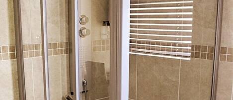 A walk-in shower with a glass door and a showerhead.
