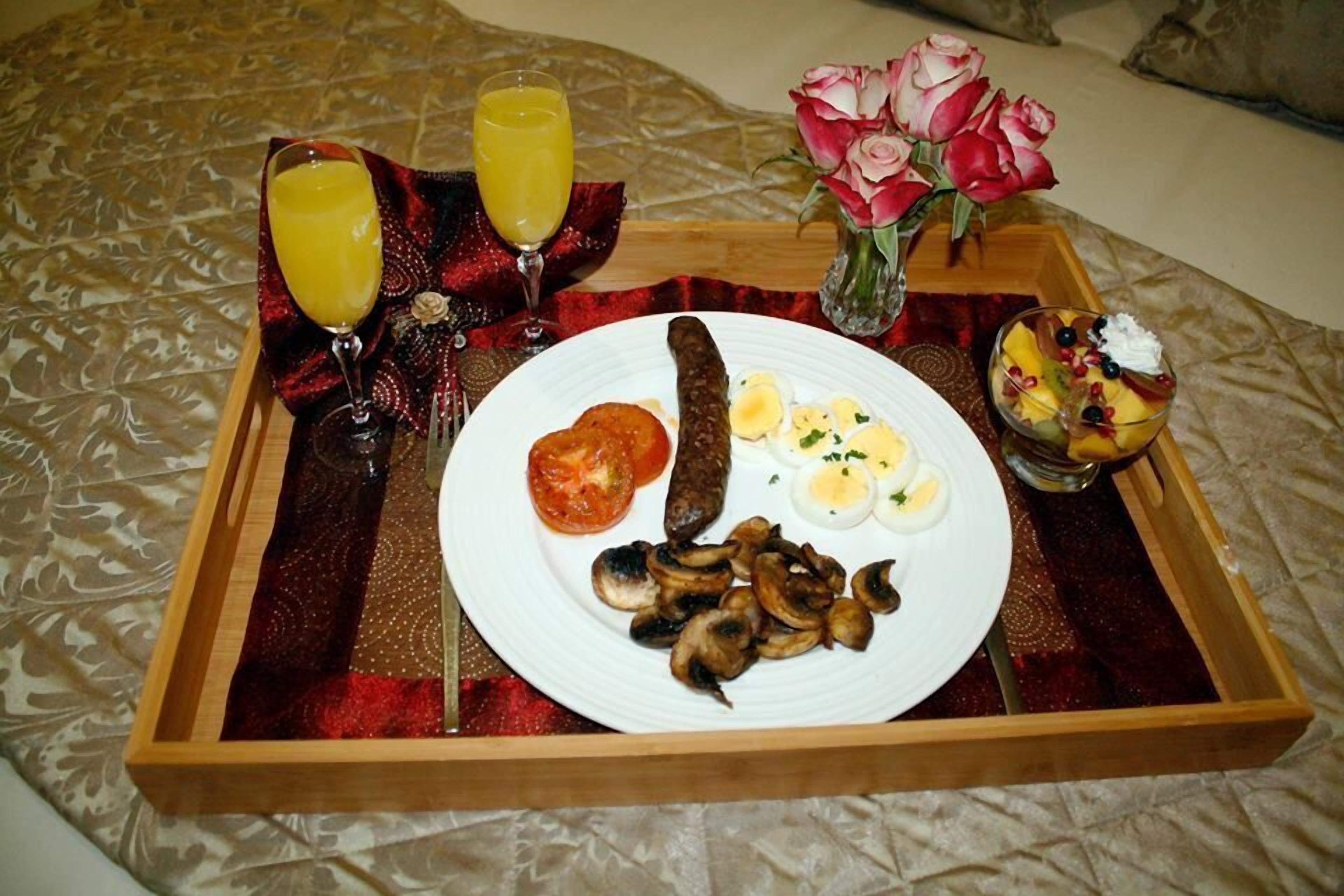 A tray with food and drinks on a bed.