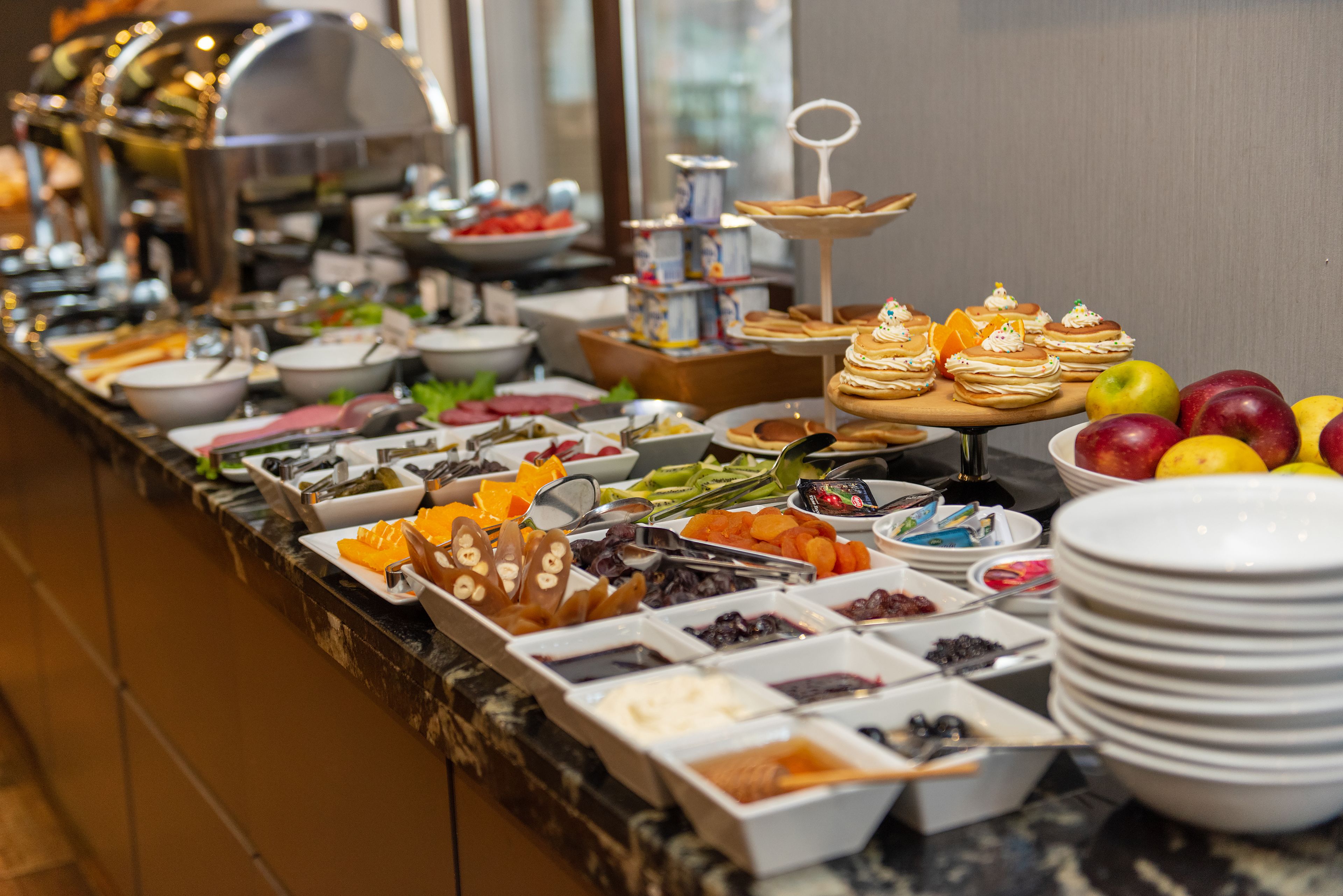 Buffet com diversos alimentos e uma saladeira de frutas.