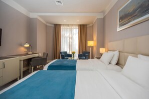A hotel room with two beds, a desk, a chair, a lamp, and a painting on the wall. - City Avenue (Tbilisi)