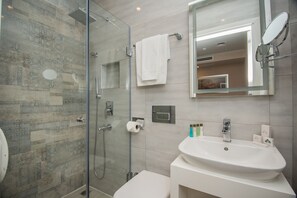 A modern bathroom with a glass shower enclosure, a white sink, and a large mirror. - City Avenue (Tbilisi)