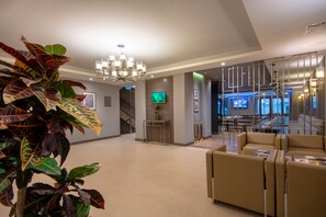 A modern hotel lobby with a chandelier, seating area, and a staircase leading to another level. - City Avenue (Tbilisi)
