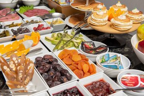 A buffet with various food items including fruits, pastries, and condiments. - City Avenue (Tbilisi)