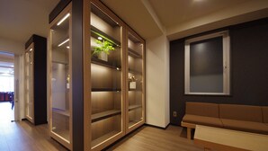A modern interior with wooden flooring, a brown sofa, and a glass-fronted cabinet with a plant. - Urbain Kyoto Kiyomizu Gojo (Kyoto)