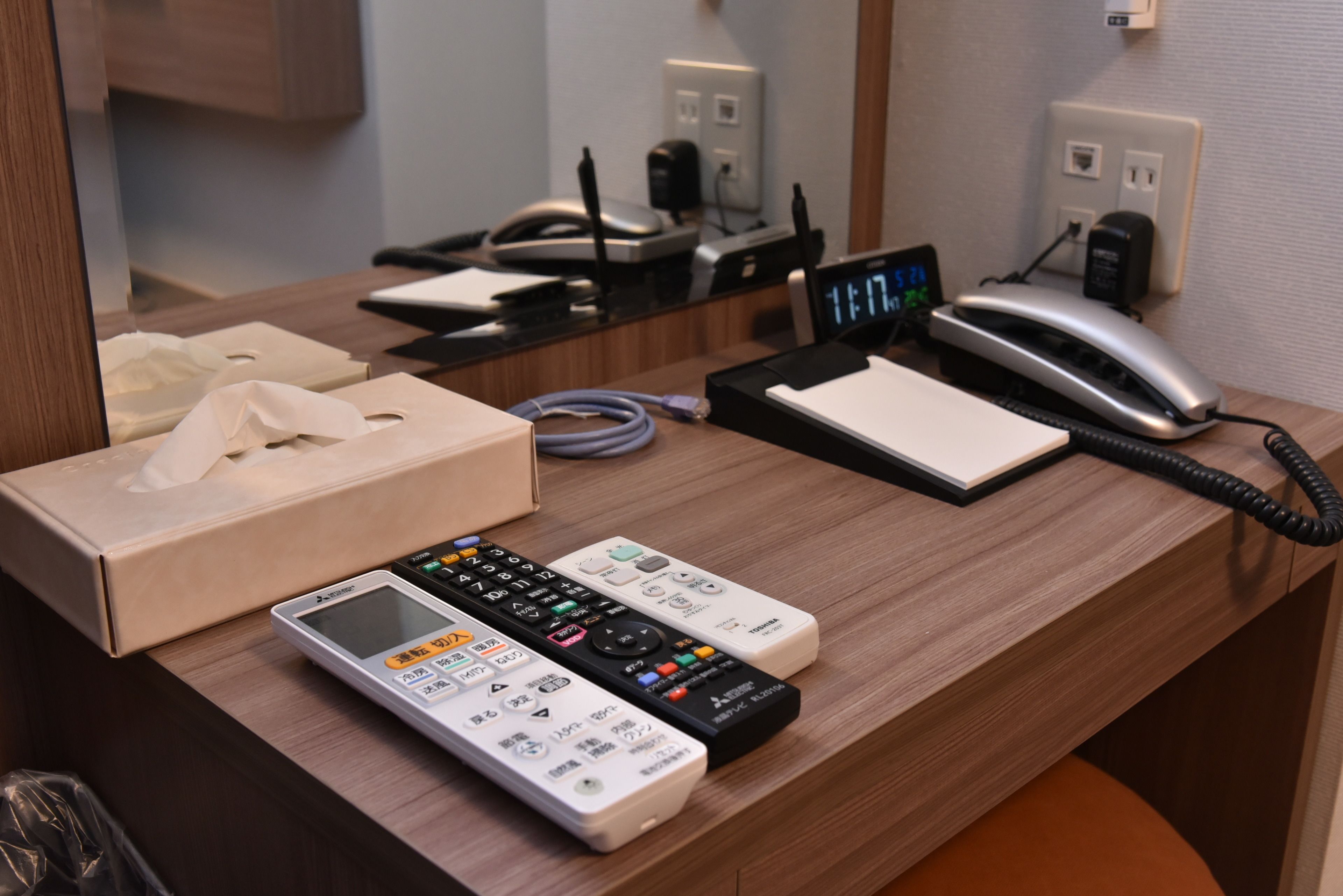A hotel reception desk with a telephone, a digital clock, a notepad, and a tissue box.