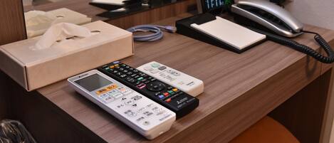 A hotel reception desk with a telephone, a digital clock, a notepad, and a tissue box.