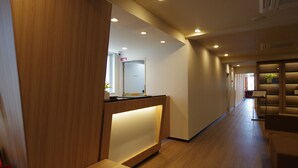 A hotel reception area with a wooden reception desk, a sign indicating a room for sale, and a hallway leading to other rooms. - Urbain Kyoto Kiyomizu Gojo (Kyoto)