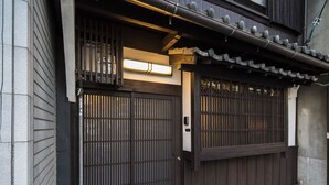 En traditionel japansk port med skydedøre, et tag med fliser og et lille, oplyst vindue.