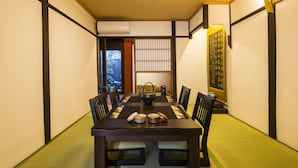 Et traditionelt japansk rum med tatamimåtter, et lavt bord med et te-service og skydedøre.