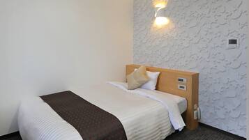 A hotel room with a bed, a headboard with controls, a wall-mounted light, and a thermostat.