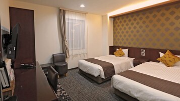Habitación de hotel con dos camas, un escritorio, una silla, un televisor y una ventana con cortinas.
