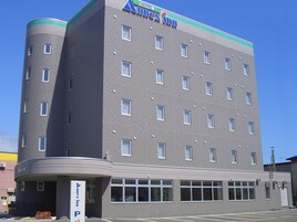 Un hotel de varios pisos con un diseño moderno, que destaca un letrero grande que dice 'AXIS' en la parte superior.