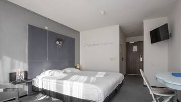 Habitació d'hotel moderna amb un llit gran, una taula de nit i un escriptori amb una cadira.