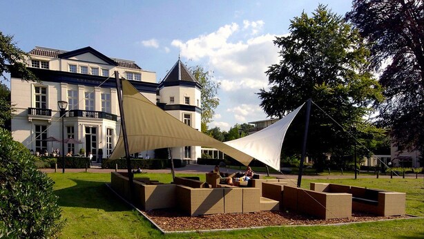 Une cour dotée d’un espace extérieur aménagé avec des sièges et d’une grande structure ressemblant à une voile.