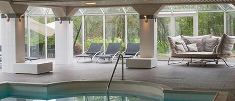 Uma área de piscina com espreguiçadeiras e um sofá, janelas amplas e um teto com padrão de grade.