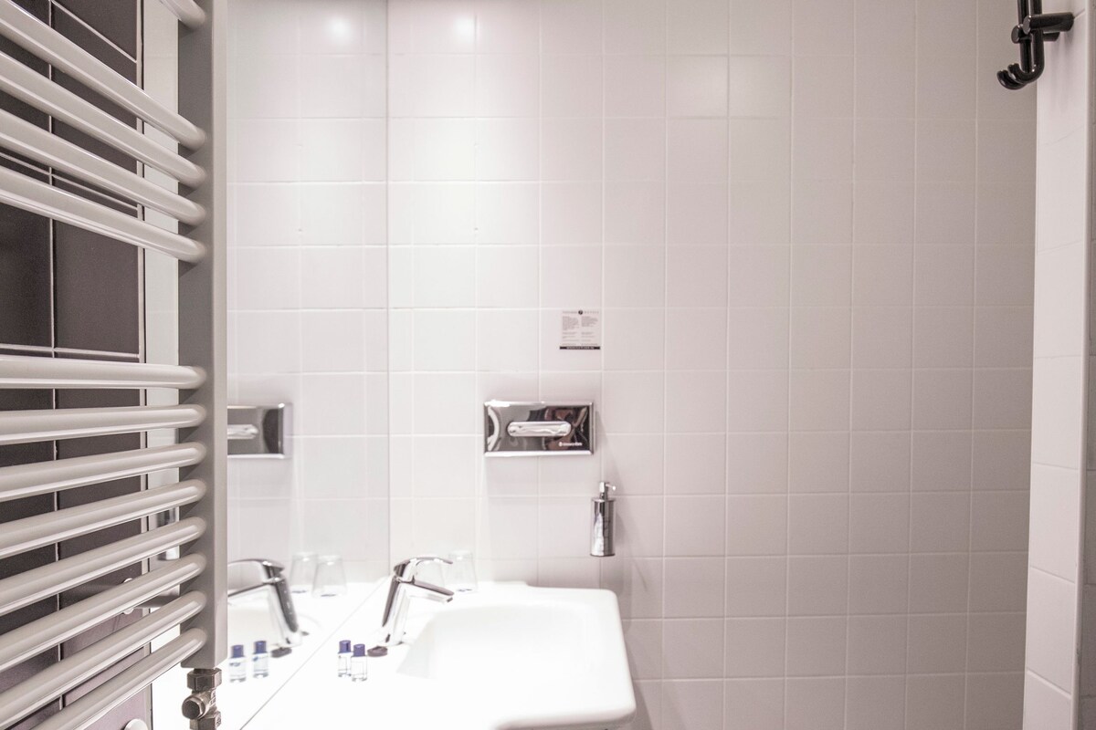 Un baño moderno con piso a cuadros, un lavamanos blanco y una ducha.