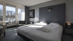 Una habitación de hotel moderna con una cama grande, una silla, un escritorio y vistas al exterior.