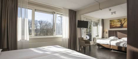 A hotel room with two beds, a desk, a chair, a TV, and a painting on the wall.