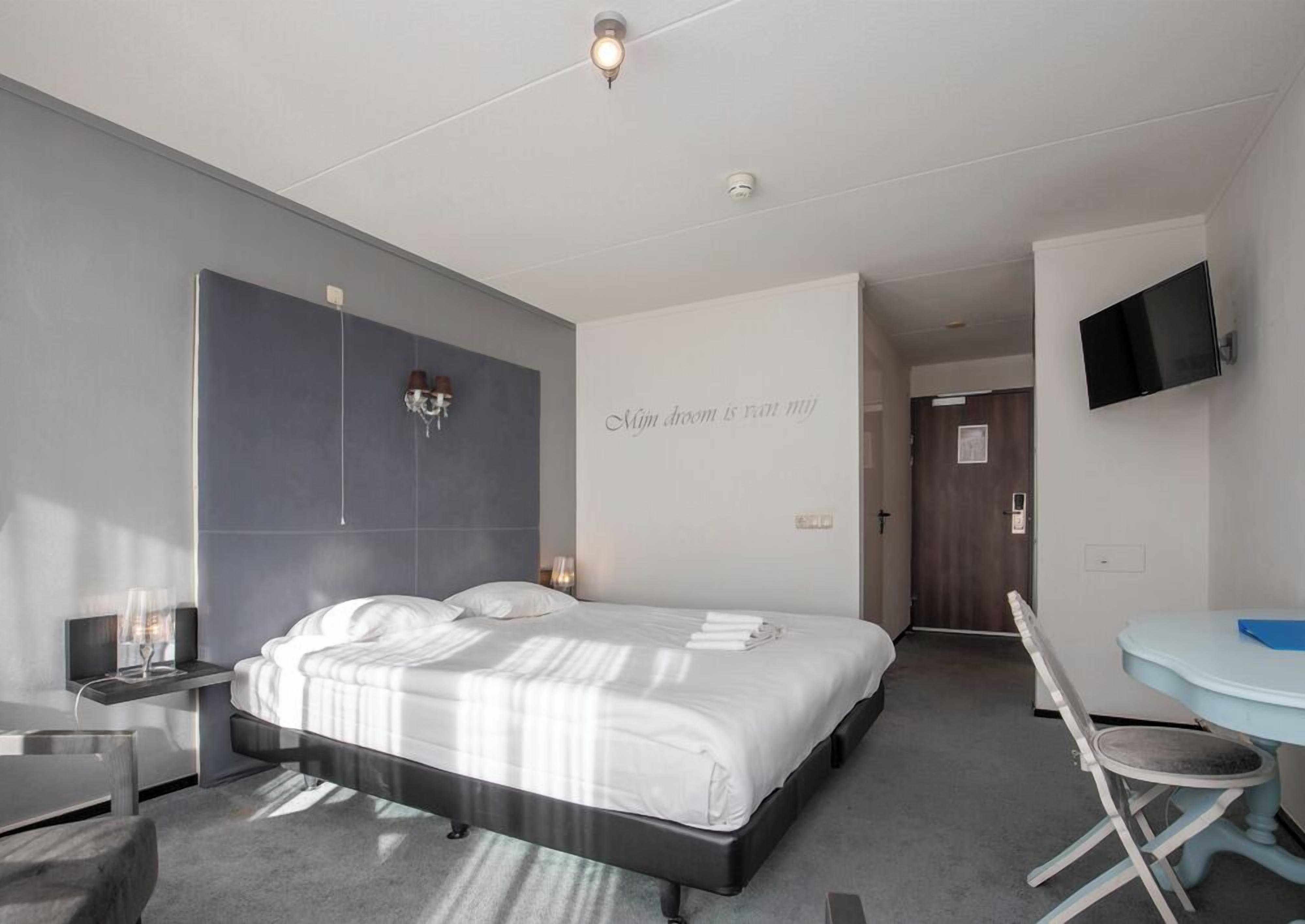 Una habitación de hotel moderna con una cama, una mesita de noche y un escritorio con una silla.