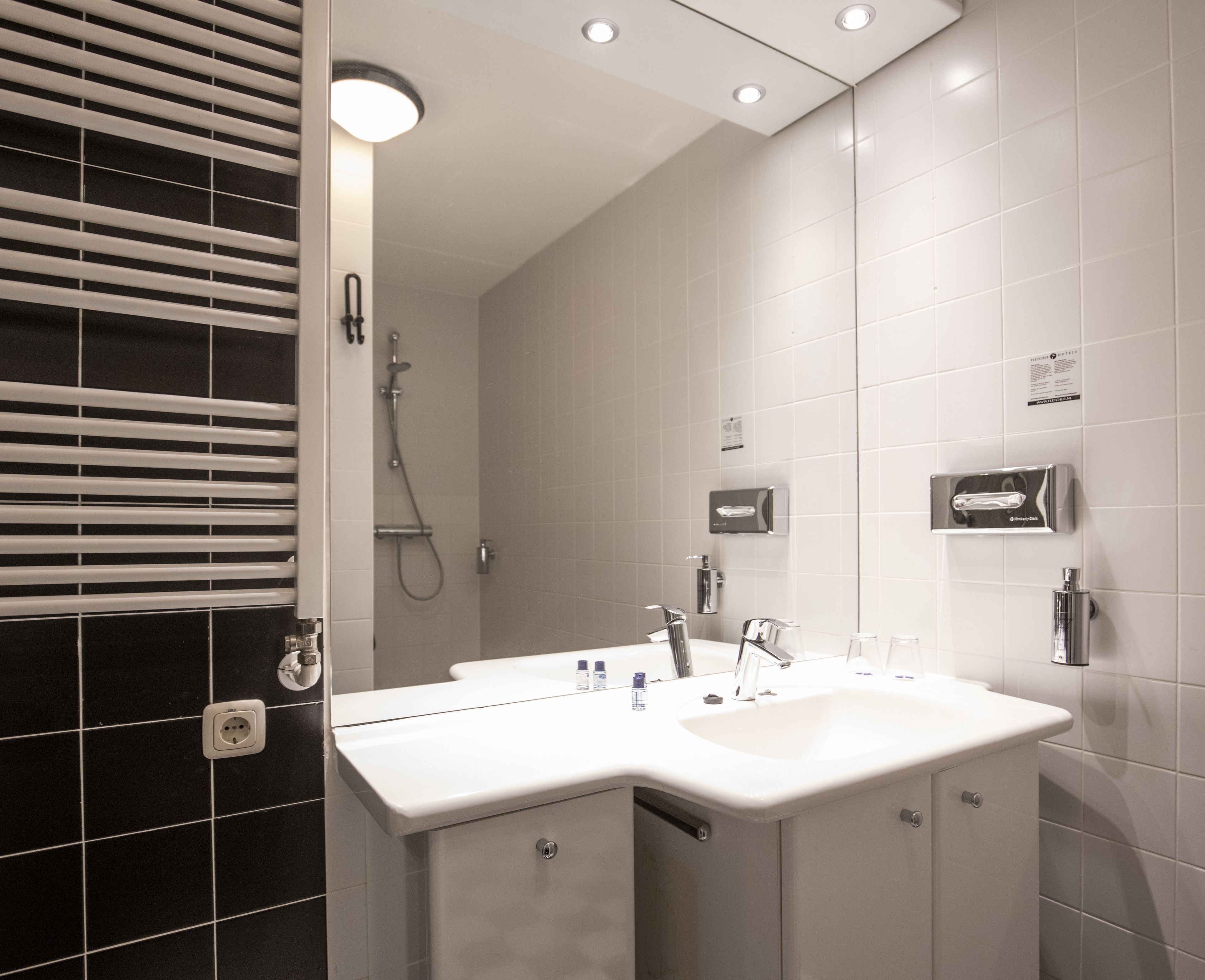 A modern bathroom with a white sink, a mirror, and a shower.