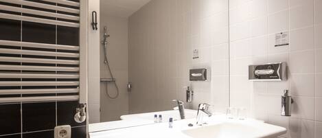 A modern bathroom with a white sink, a mirror, and a shower.