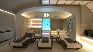Ein Spa-Raum mit vier Liegen, einem Massagetisch und einem Empfangsbereich mit einem digitalen Bildschirm.