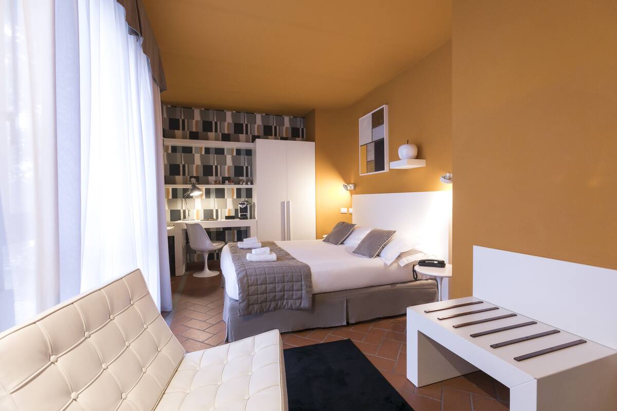 Una habitación de hotel moderna con cama, escritorio, silla y sofá.