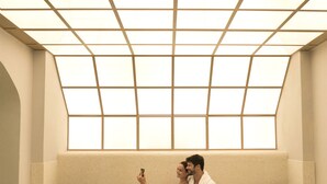 Ein Wellnessraum mit großem Fenster, einer gepolsterten Bank und einem Massagetisch.