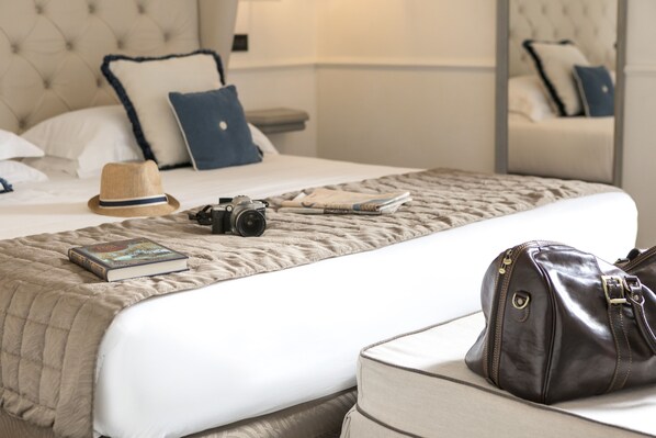 Un lit bien fait, avec une couverture matelassée, un livre, un appareil photo et un sac à main posés sur un oreiller blanc.