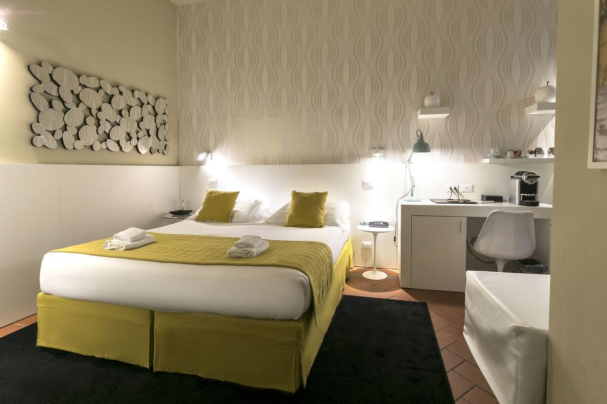 Habitación de hotel con cama, escritorio, silla y pared con diseño decorativo.