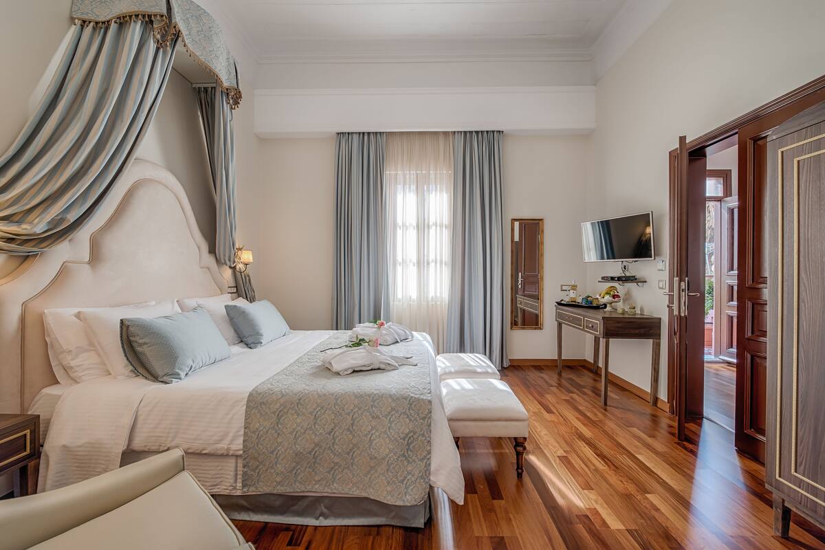 A hotel room with a large bed, a bedside table, a desk, and a television.