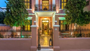 Un edificio de dos plantas con un balcón, una entrada de azulejos y una fachada bien iluminada.