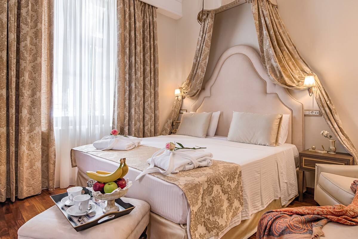 A bedroom with a large bed, a bedside table, a chair, and a wooden floor.