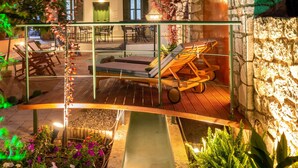 Un patio con muro de piedra, asientos al aire libre y una pequeña fuente.