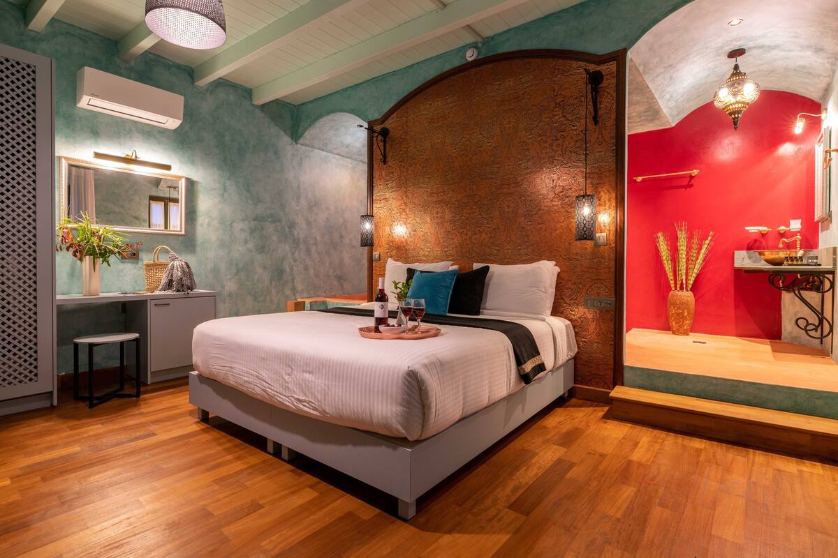 A bedroom with a bed, bedside table, and a desk with a chair.